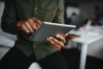 Close-up of businessman's finger touching screen of a digital tablet at the office