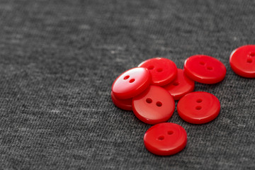 Bright red buttons. Gray fabric. Blurred background. The concept of the clothing industry and decor.