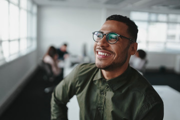 Portrait of a handsome casual businessman wearing black eyeglasses in office smiling - 292951007