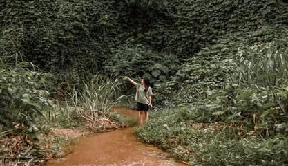 Happy tourist woman Jungle Trekking  on holiday relaxing Concept. hipster asian woman exploring dense tropical jungle and rainforest Outdoor photo . model posing and smiling  during Summer travel .