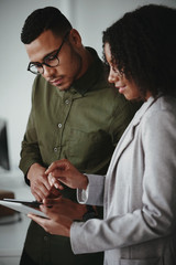 Young african american businessman and businesswoman discussing project on digital tablet computer...