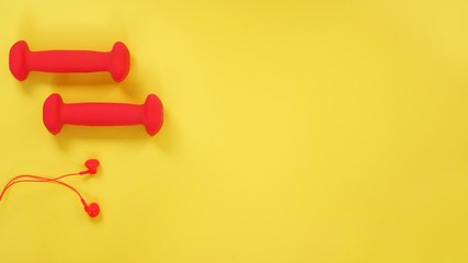 Top view of dumbbell, headphones, carpal expander, apple on a yellow background with space for text. Creative flat lay sport and fitness concept.