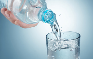 pouring water into a glass on blue background