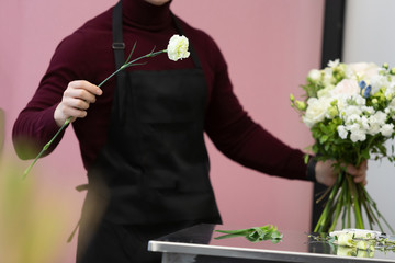 Young unidentified male florist aprons shows how to make a bouquet of white flowers in his master class. Wedding decoration concept