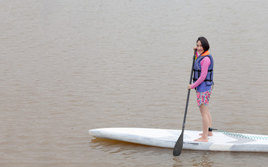 SUP / Stand up Paddle Board Get ready . Happy woman and group friends taking Stand Up Paddle Board ( SUP ) Surfing  on a river lake water in holiday . Water sport, happy active summer vacation .