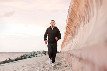 Young male jogging on a beach at sunrise. Motion blur effect. Concepts: well-being, vitality, healthy life, vacation, sport, training