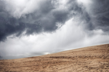 Sandstorm in a dry desert under a cloudy sky