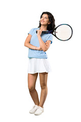 A full-length shot of a Young tennis player woman looking up while smiling over isolated white background