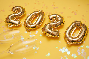 Gold foil balls on yellow background. Inflatable figures 2020. Concept new year, Christmas. Copy...