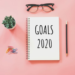 New year concept. Goals 2020 and notepad, smartphone, stationery on pink pastel color with copy space