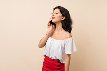 Young woman over isolated background keeping a conversation with the mobile phone