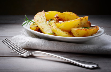 Roasted potatoes with fork on wood background