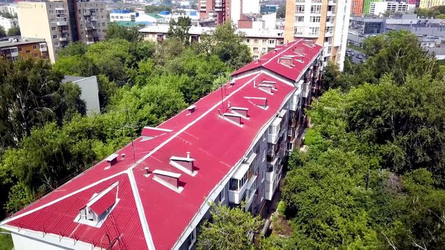 Top view of red roof of multi-storey residential building. Stock footage. Top view of red roof of multi-storey residential building
