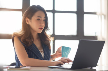 Young Asian female sitting and using Laptop computer in the office.