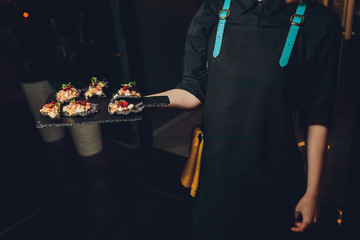 A waiter with a tray of snacks at a banquet or reception. Catering buffet at party.