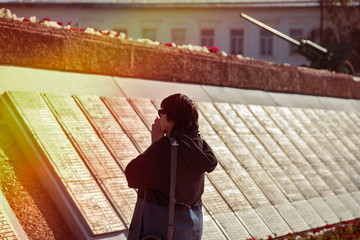 A woman stands in front of a memorial wall with the names of the victims of the second world war. She folded her hands in front of her face, her face sad. Defocused image.