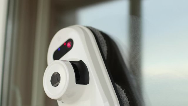 Vacuum cleaner robot cleaning window in high building outdoor.