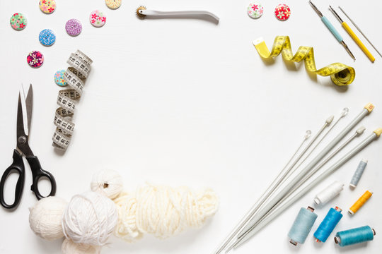 Sewing flat lay composition with threads, fabrics, scissors, buttons and sewing accessories on a white background, flat lay.Set of sewing thread and accessories
