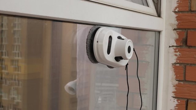 Vacuum cleaner robot cleaning window in high building outdoor.