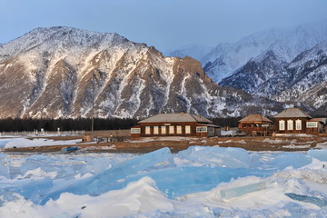 Lake Baikal in the winter. Crystal clear ice covers the lake. Coastal stones and rocks are covered...