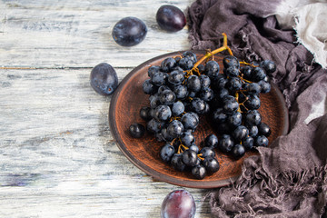 Large, black, wine grapes. It is covered with a white coating called yeast. With the help of them, wine is obtained. Drops of water on the berries, next to a gray fabric for decoration. 