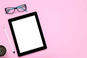 Tablet computer with glasses, pencil and cactus on pink background