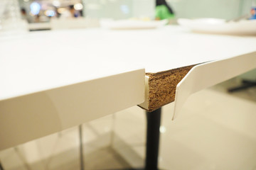 Closeup of white pvc sheets peeled off from the edge of dining table after using for years Defective furniture products