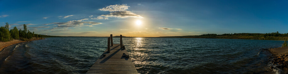 Fototapeta na wymiar Wooden jetty at a beautiful lake, summer sunset