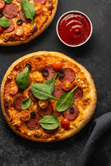 Freshly baked homemade pizza on a black background. View from above.