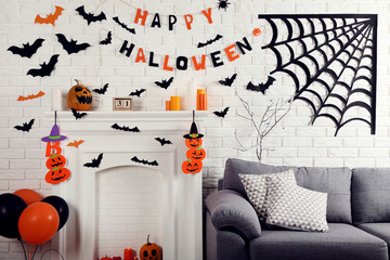 Halloween decorations on white fireplace with orange pumpkins and balloons near grey couch