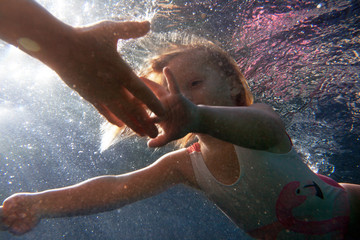 A little girl swimming to her dad shot from underwater