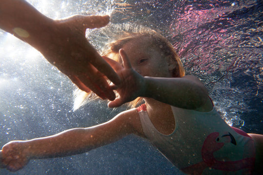 A little girl swimming to her dad shot from underwater