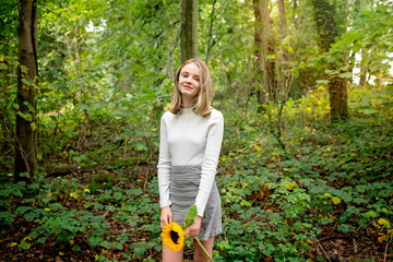 Girl holding a sunflower in the woods