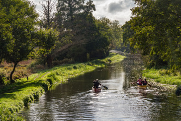 Middle aged senior people kayak or canoe down a beautiful river in the countryside in Surrey,...