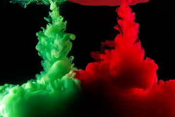 A cloud of colored acrylic paint in water. A drop of colorful ink dissolves in water on a black background. Abstract background.