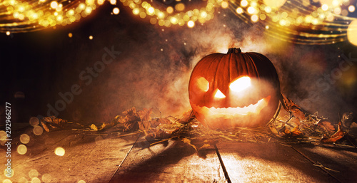 Spooky halloween pumpkin on wooden planks in dark cellar.