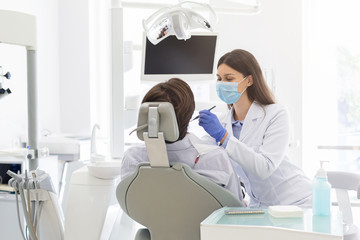 Young female dentist making treatment to patient
