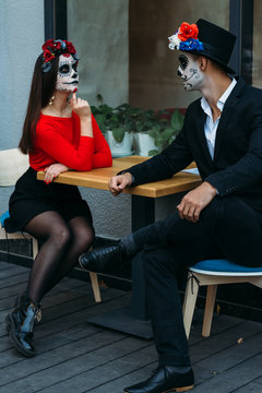 A couple, wearing skull make-up for. All souls day. Boy and girl sugar skull makeup.painted for halloween. dead in the city. zombie walk.