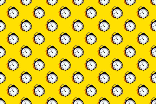 Many black classic style alarm clock with hard shadow isolated on yellow background. Smile time concept. New Year pattern
