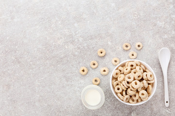 Fototapeta na wymiar Corn rings with bottle of milk and spoon on grey background