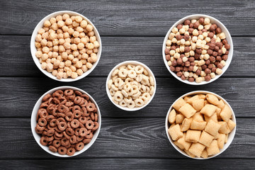 Various corn flakes in bowls on black wooden table