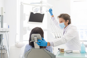 Young handsome dentist comforting female patient sitting in chair