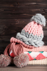 Obraz na płótnie Canvas Folded knitted sweaters with hat and scarf on wooden background