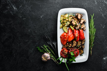 Grilled vegetables on a plate. Tomatoes, eggplants, mushrooms, zucchini. Dishes, food. Top view. Free space for your text.