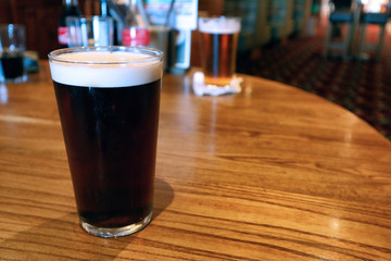 Pint of beer on a table with other in background