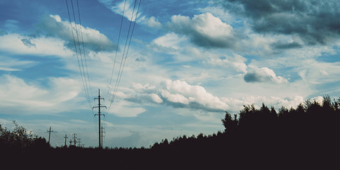 Evening sky at sunset background. Dark clouds hanging above horizon. Majestic cloudscape with power line. Grey cloudlets bringing rain. Countryside skyline in twilight time