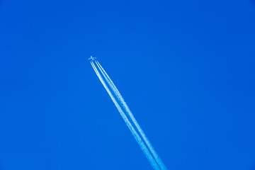 Flieger am strahlend blauen Himmel mit Kondensstreifen