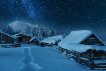 Fairytale landscapes of the winter Carpathian Mountains with a charming milky way in the sky tourist tents and snowy houses in the valleys