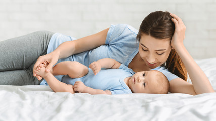 Young mother and newborn baby lying on bed at home