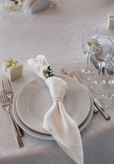 table setting: plates, forks, knives, knotted napkin, glasses, small gift box